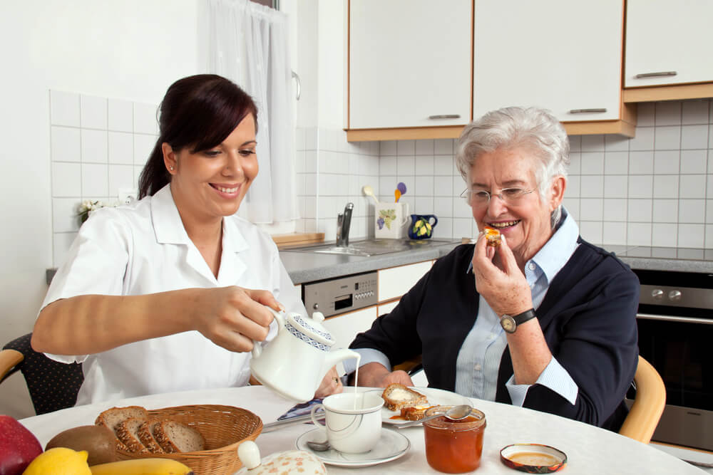 home carer having food with senior lady